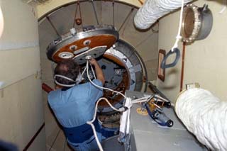 Mir-24 flight engineer Pavel Vinogradov opens the hatch in the Docking Module (DM) on the Mir.